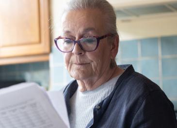 A woman in a kitchen reading paperwork
