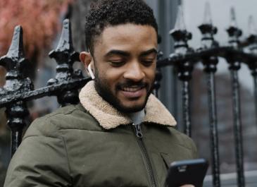 A man standing in front of railings looking at a phone