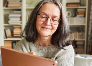 A woman is smiling while scrolling on her iPad