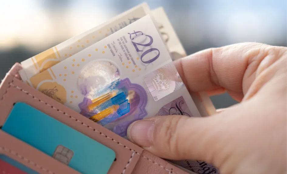 Decorative image of a person taking money out of a wallet.
