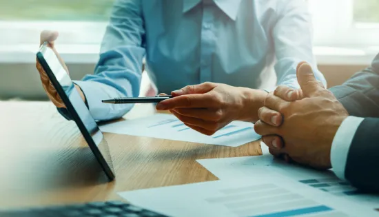 Two businessmen review information on an tablet.