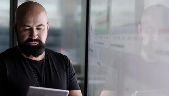 Man looking at tablet with data reflected