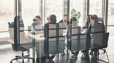 A group of office workers sat around a meeting table
