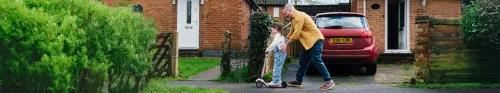 Photo of a father pushing his daughter on a scooter