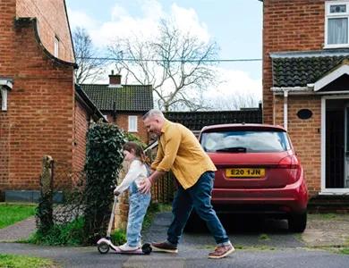 Photo of a father pushing his daughter on a scooter