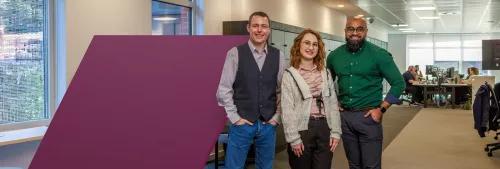 Three people standing in a row by spotlight