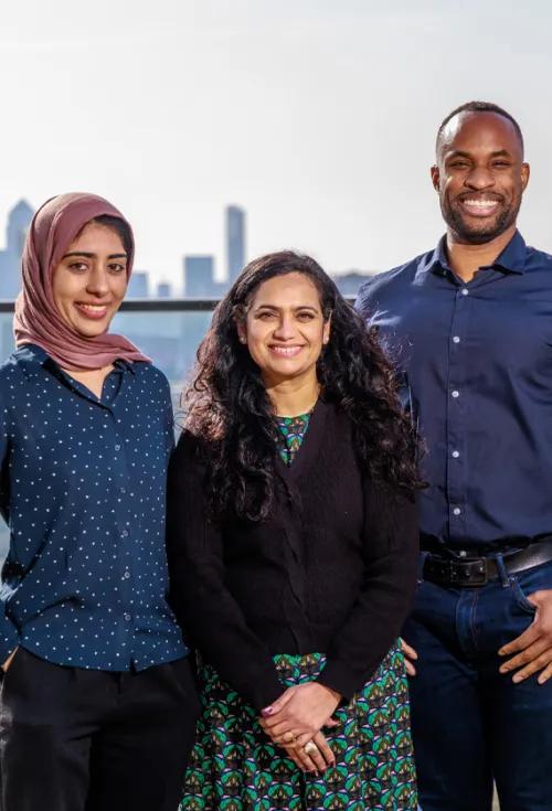 Three people standing in a row by skyline