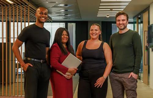 Four multicultural colleagues standing in office