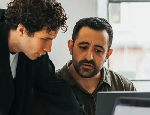 Photo of 2 people looking at a laptop screen