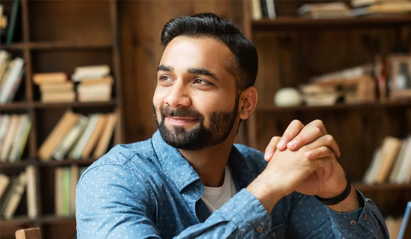 A man is smiling and looking away from the camera.