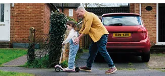 Photo of a father pushing his daughter on a scooter